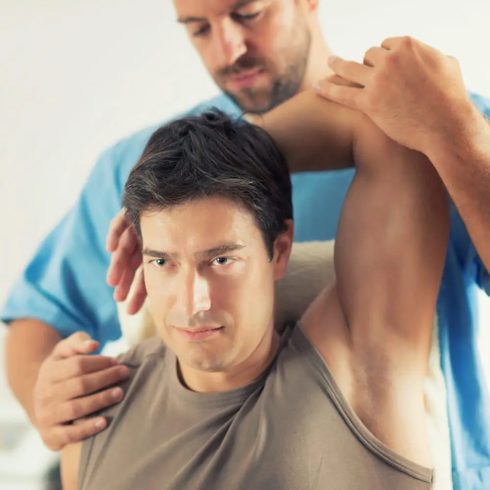 chiropractor adjusting male patients shoulder pain treatment in fort wayne