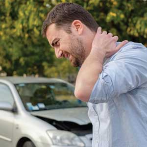 A man holding the back of his neck that is in pain due to whiplash