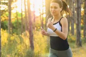 A woman jogging in sportswear along the woods early in the morning