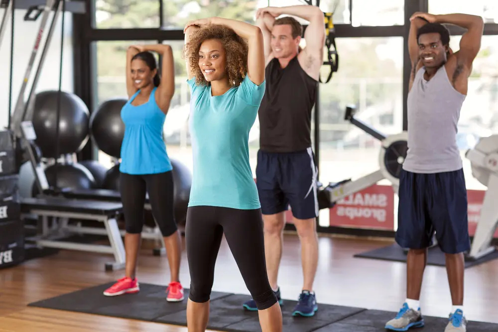 four people stretching their arms on a gym