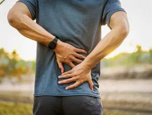 man holding his lower-back due to pain