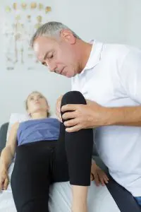 Chiropractor examining female patients knee 