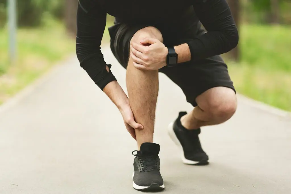 young man holding his ankle to to an injury