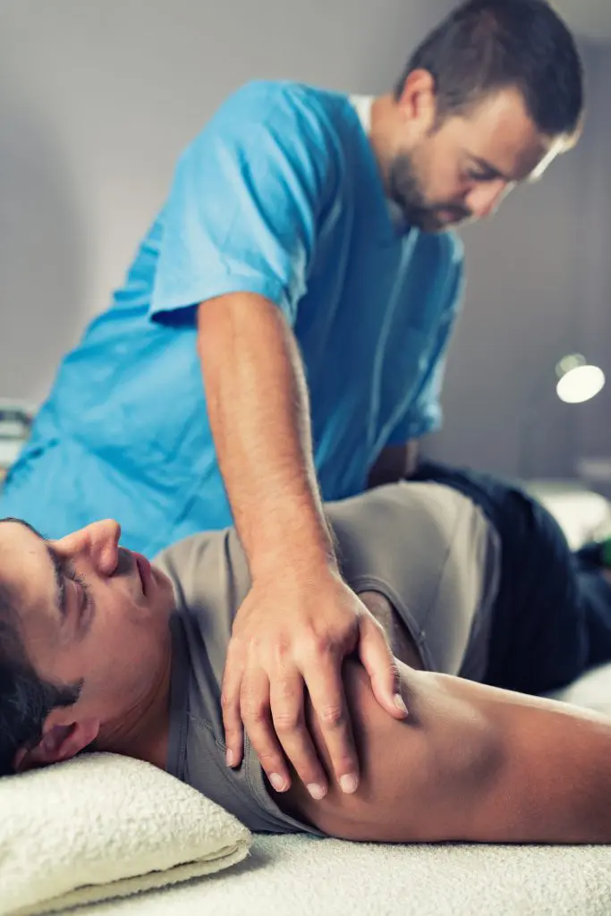 chiropractor making spinal adjustment on male patient for back pain treatment 