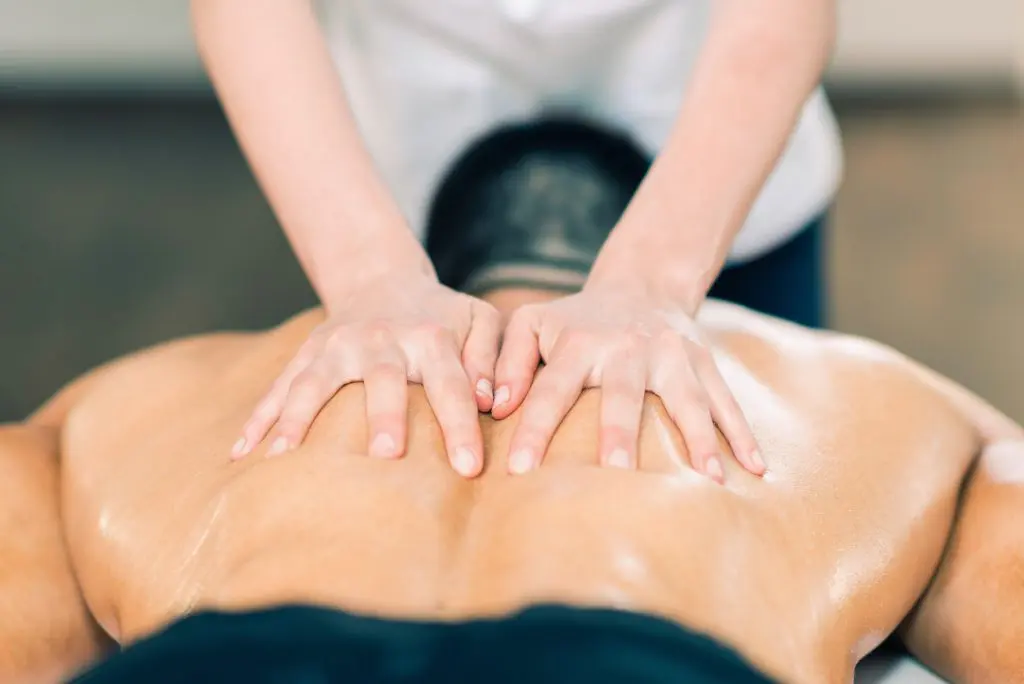 massage therapist massaging the back of her male patient 