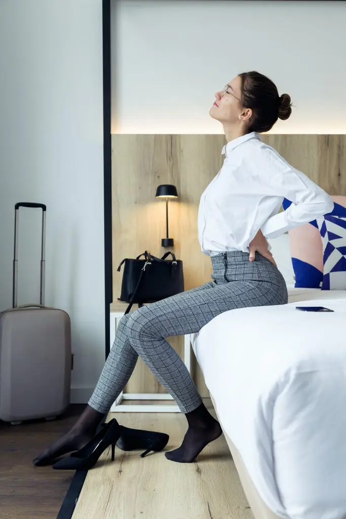 young woman sitting on her bed having back pain