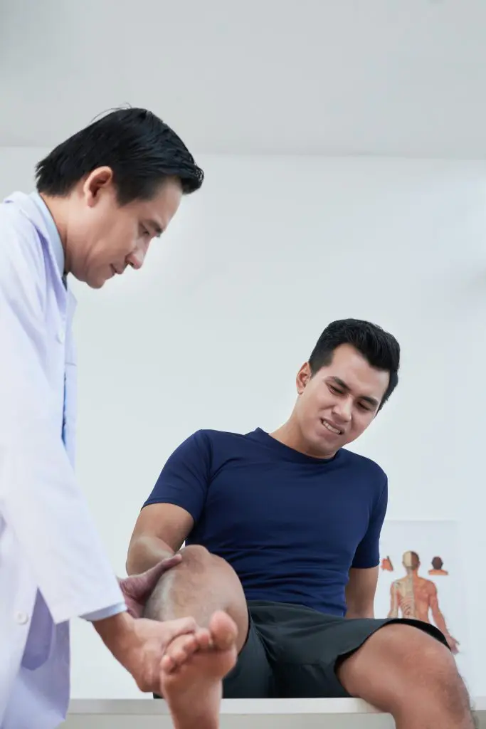 chiropractor examining patient knee after getting injured fromauto accident | auto accident injury treatment in Fort Wayne