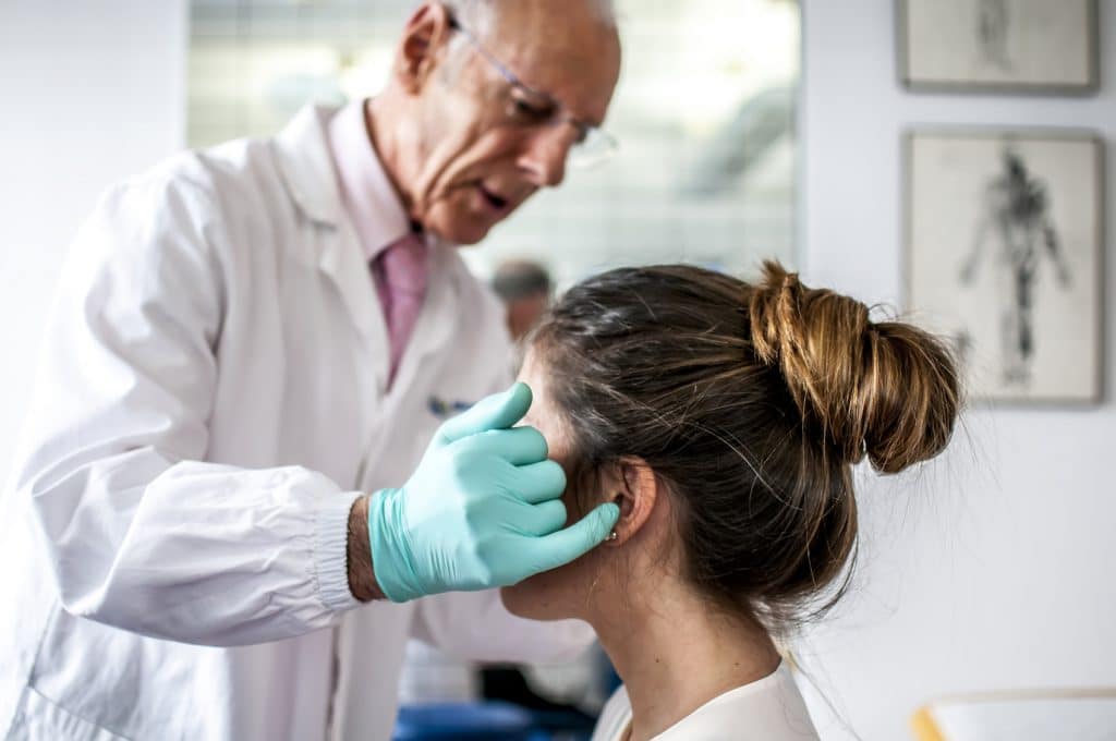 chiropractor examining a female patient's head