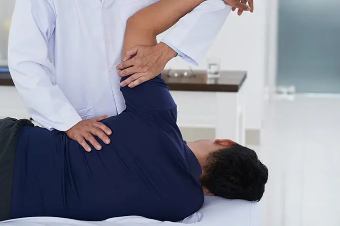 Chiropractor examining a patient with frozen shoulder pain treatment in fort wayne