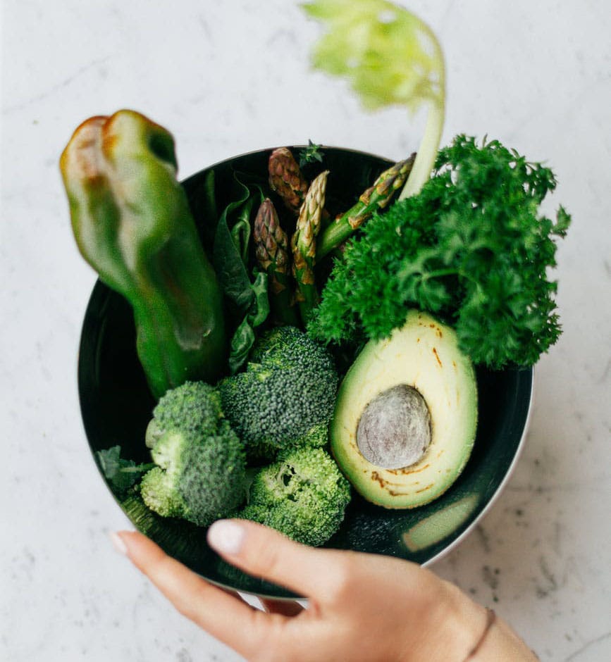 green fruits and vegetables in a bowl held by a hand taken in overview angle, anti inflammatory foods