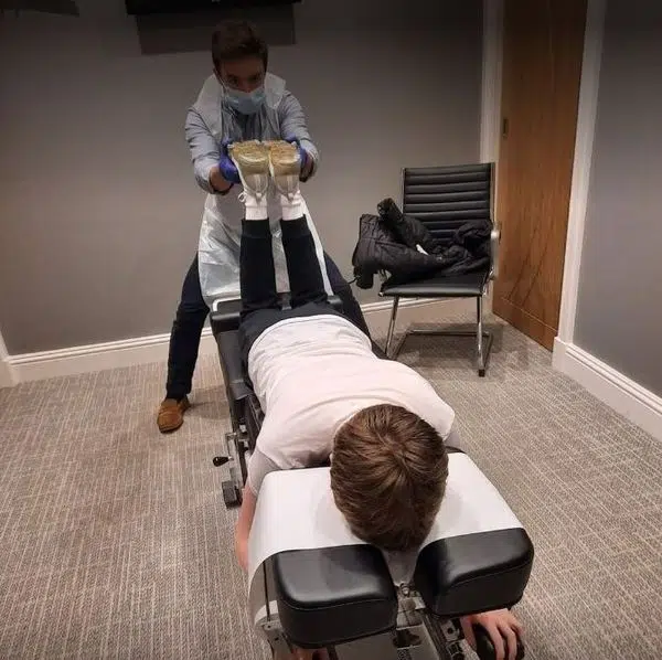 Chiropractor is doing the Thompson Drop Technique Assessment to the patient.