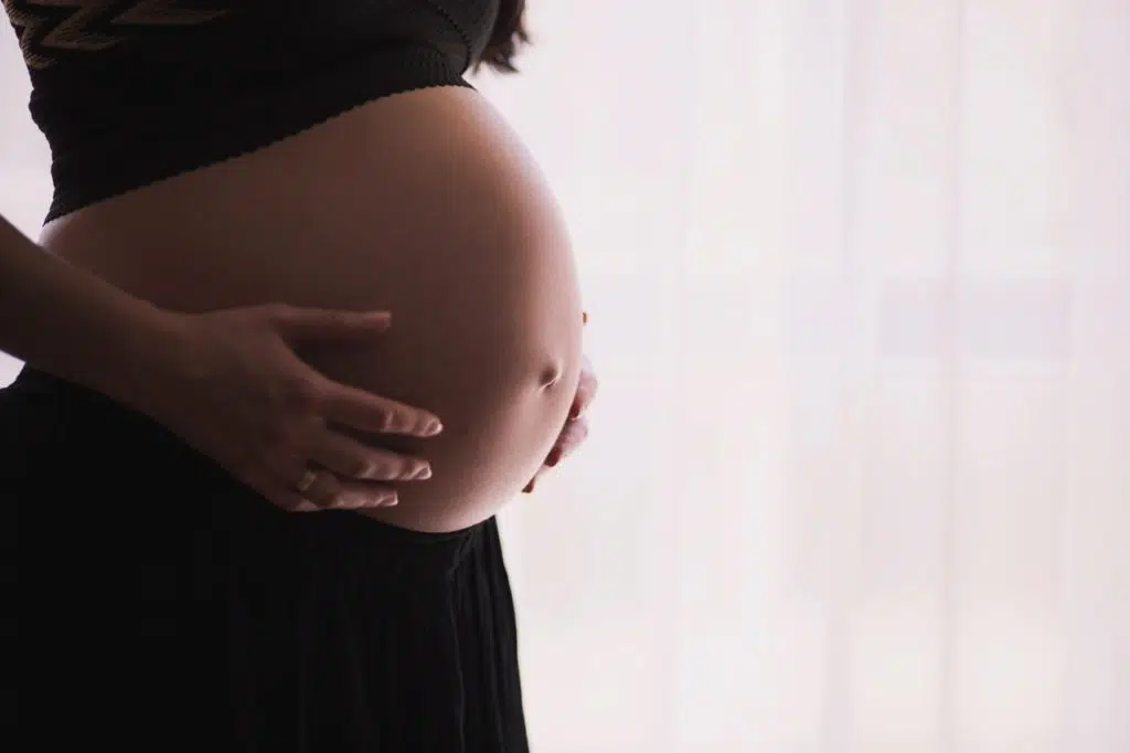 Pregnant woman is holding her belly button