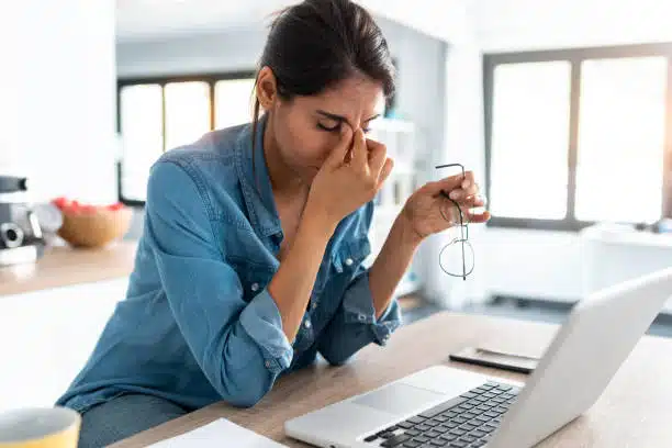 Shot of stressed business woman working from home on laptop looking worried, suffers from migraines