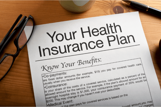 Health insurance plan and policy documents on the table.