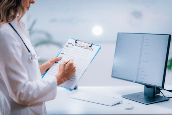 Chiropractor is checking a patients health insurance information in the system.
