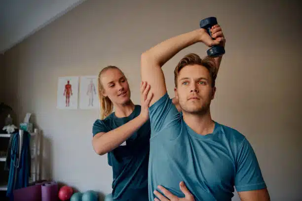 chiropractor helping man exercise with dumbbells.