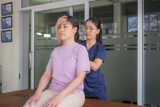 Asian woman patients having chiropractic back and shoulder adjustment with female chiropractor.