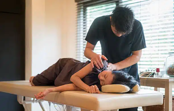 Asian chiropractor aligning a female patient at his practice center.