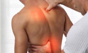 Man suffers from back pain getting checked by a chiropractor