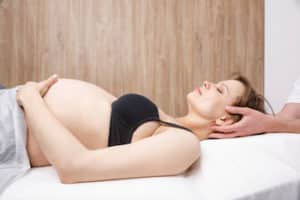 Pregnant woman getting chiropractic treatment starting from her neck