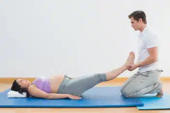 Chiropractor helping pregnant woman prepare for labor and delivery with exercises to maintain proper body alignment.