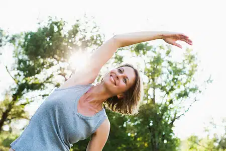 smiling woman doing a stretch while outdoors