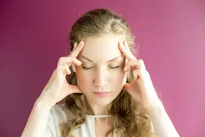 woman with chiropractic adjustments alleviate migraine symptoms standing on a pink background