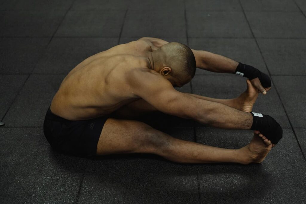 Athlete performing a seated stretch to rebuild strength and flexibility during injury rehabilitation.