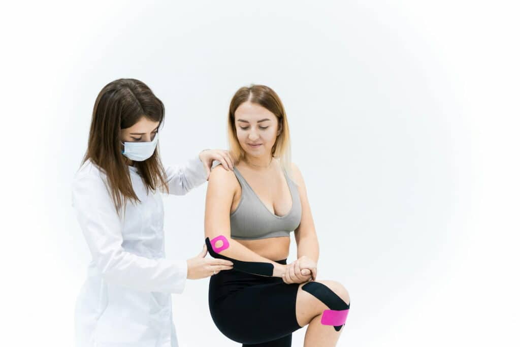 Sports medicine provider applying therapeutic taping to support an athlete during injury rehabilitation.